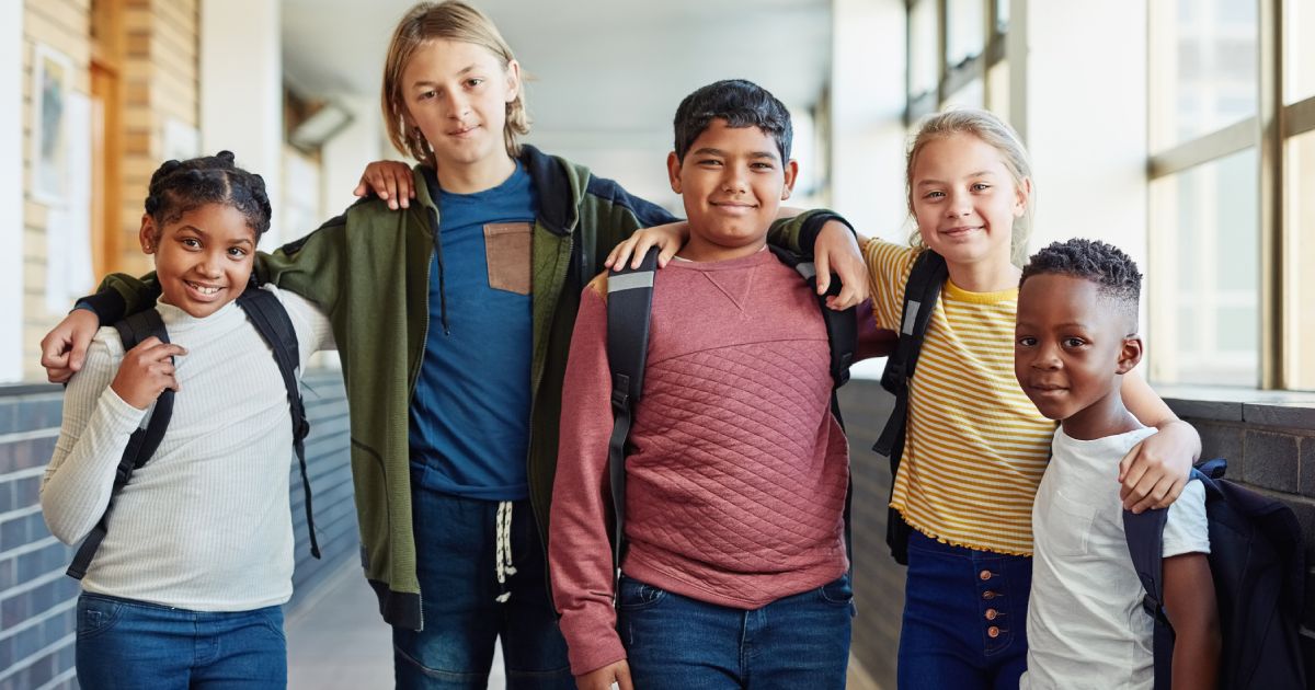 Portrait of a group of young children standing together in the hallway of a school