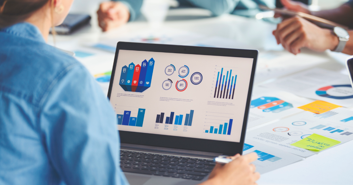 Group of people working with paperwork on a table, with documents and a laptop that both have figures, graphs and charts