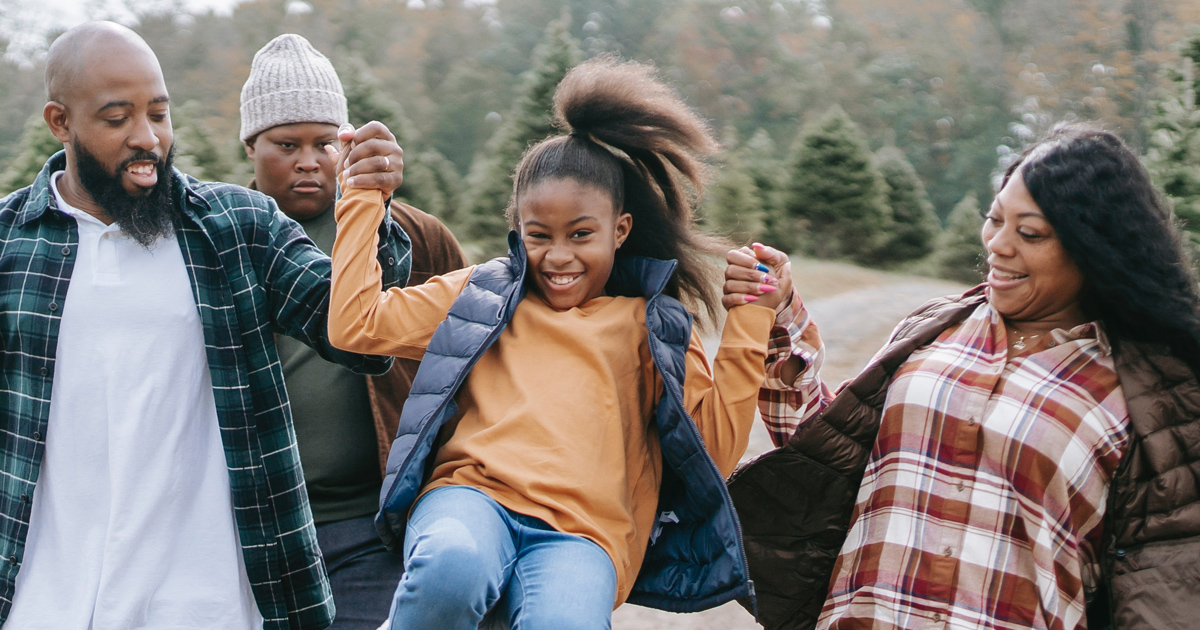 A father and mother lift a child.