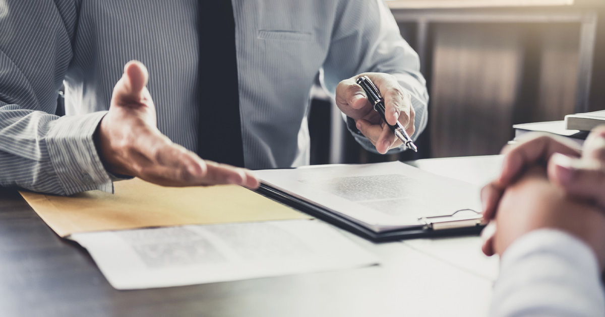 a person holding a pen over a clipboard