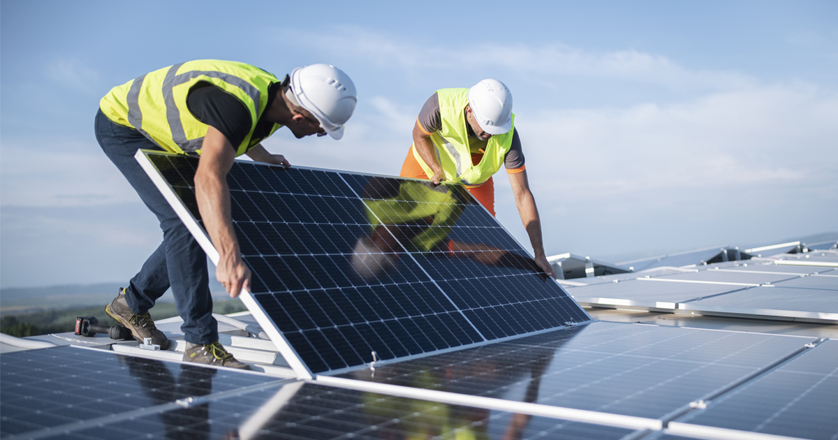 men wearing safety vests and white helmets working on solar panels